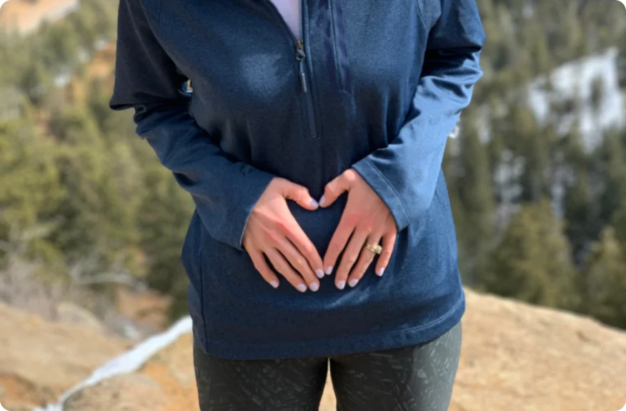 Vrouw die zich met handen op de buik bevindt, die de mogelijkheid van betekenisvolle en bevredigende intieme ontmoetingen na een stomaoperatie vertegenwoordigt.